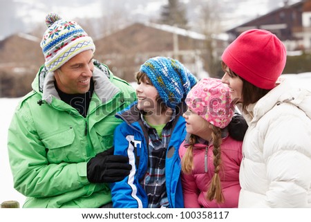 Portrait Of Family Wearing Winter Clothes In Snowy Landscape