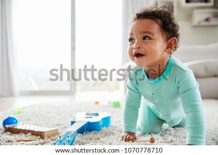 Happy mixed race toddler boy crawling in sitting room