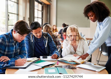 Group Of High School Students With Female Teacher Working At Desk