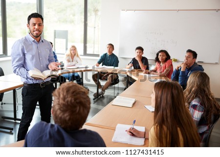 Male High School Tutor With Pupils Sitting At Table Teaching Maths Class