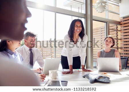 Smiling female manager listening to colleagues at a meeting