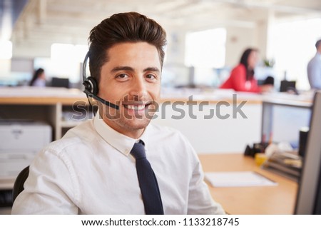Hispanic male call centre worker smiling to camera, close-up