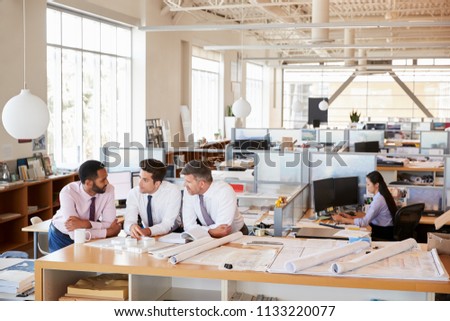 Three male architects in discussion in an open plan office