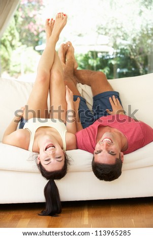 Couple Lying Upside Down On Sofa