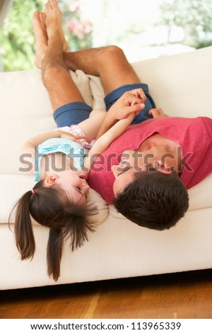 Father Lying Upside Down On Sofa With Daughter