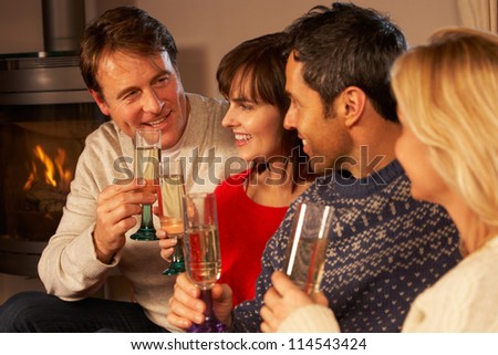 Group Of Middle Aged Couples Sitting On Sofa With Champagne