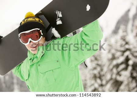 Teenage Boy With Snowboard On Ski Holiday In Mountains