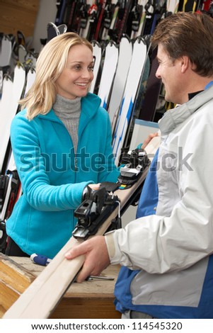 Female Sales Assistant Handing Skis To Customer In Hire Shop