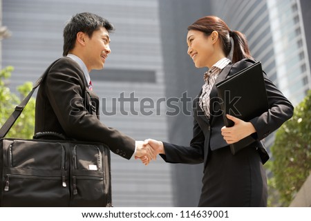 Chinese Businessman And Businesswoman Shaking Hands Outside Office