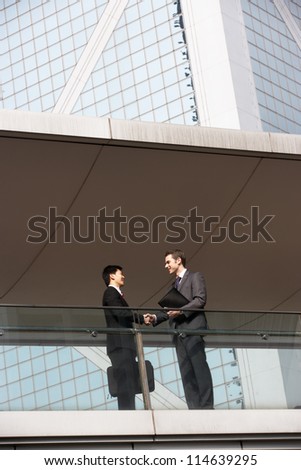 Two Businessmen Shaking Hands Outside Office Building