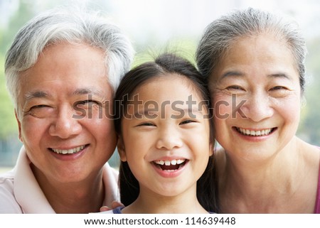 Head And Shoulders Portrait Of Chinese Grandparents With Granddaughter Ride