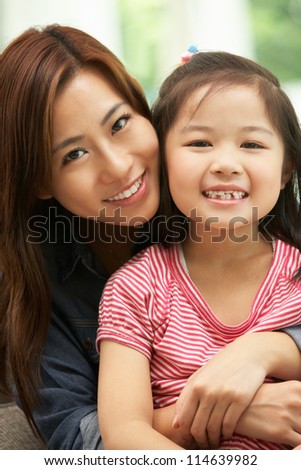 Chinese Mother And Daughter Sitting On Sofa At Home Together