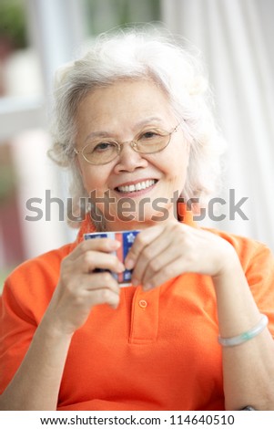 Senior Chinese Woman Drinking Tea On Sofa At Home