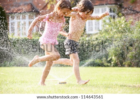 Two Children Running Through Garden Sprinkler