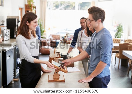 Customer at the front of the queue paying in a coffee shop
