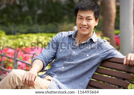 Young Chinese Man Relaxing On Park Bench