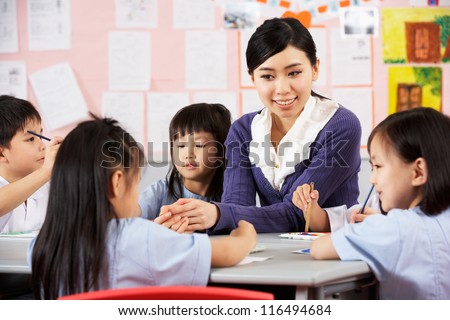 Teacher Helping Students During Art Class In Chinese School Classroom