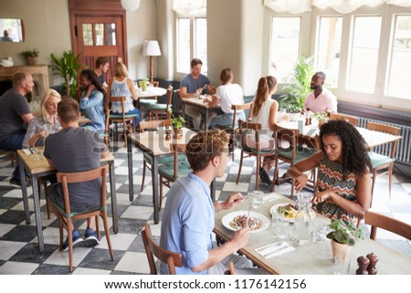 Customers Enjoying Meals In Busy Restaurant