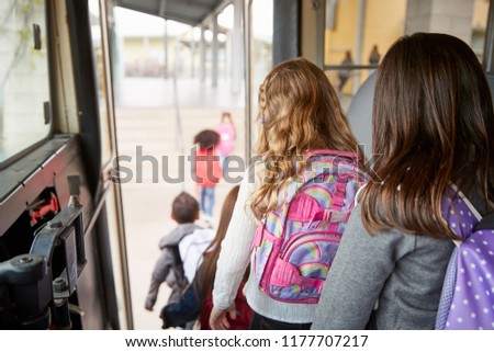 Two girls waiting behind their friends to get off school bus