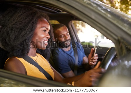 A young black man checks smartphone during a road trip