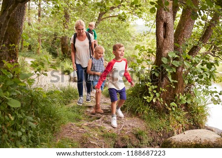 Family Hiking Along Path By River In UK Lake District