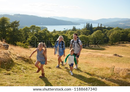 Family Climbing Hill On Hike Through Countryside In Lake District UK Together