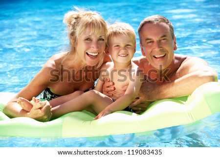 Grandparents And Grandson Having Fun In Swimming Pool