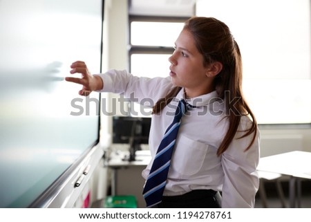 Female High School Student Wearing Uniform Using Interactive Whiteboard During Lesson