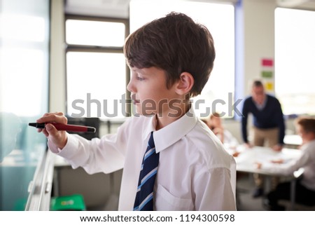 Male High School Student Wearing Uniform Using Interactive Whiteboard During Lesson