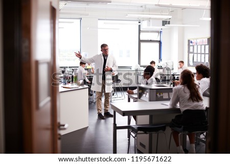 Male High School Tutor Teaching High School Students Wearing Uniforms In Science Class