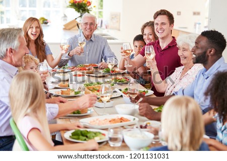 Group Of Multi-Generation Family And Friends Sitting Around Table And Making A Toast