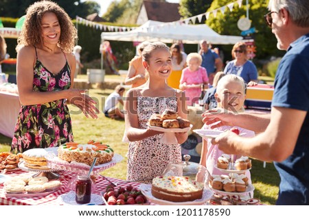 Children Serving On Cake Stall At Busy Summer Garden Fete