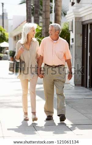 Senior Couple Walking Along Street Together