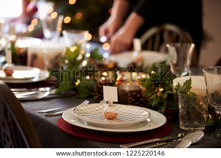 Christmas table setting with bauble name card holder arranged on a plate and green and red table decorations