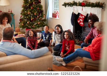 Multi Generation Family Sitting In Lounge At Home On Christmas Day