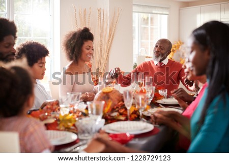 Multi generation mixed race family holding hands and saying grace before eating at their Thanksgiving dinner table, selective focus