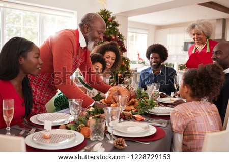 Grandfather bringing the roast turkey to the dinner table during a multi generation, mixed race family Christmas celebration, close up