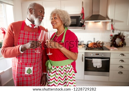 Senior black couple wearing aprons take a break from preparing Christmas dinner to make a toast, close up