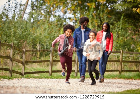 Mixed race children running ahead of their parents on a path during family walk in the countryside, low angle