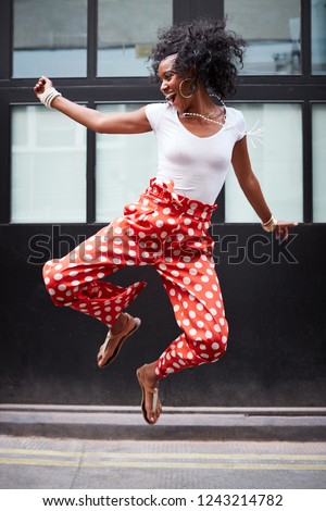 Fashionable young woman jumps up and laughs, full length