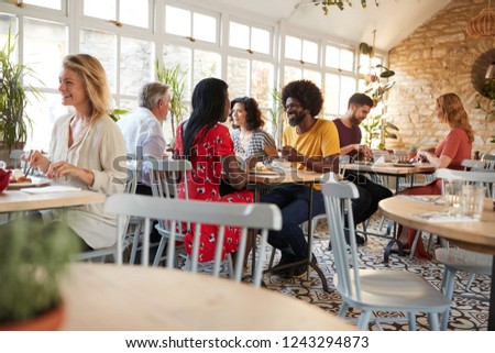 Customers eating at a busy restaurant in the day time