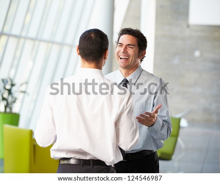 Two Businessmen Having Informal Meeting In Modern Office