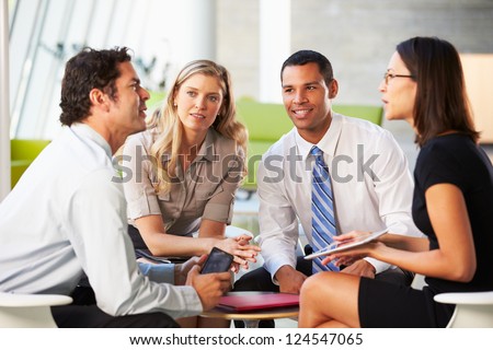 Businesspeople With Digital Tablet Having Meeting In Office