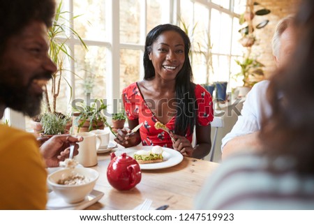 Happy young black woman eating brunch with friends at a cafe
