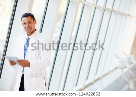 Doctor Using Digital Tablet In Corridor Of Modern Hospital