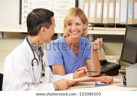 Doctor With Nurse Working At Nurses Station