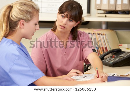 Two Nurses Working At Nurses Station