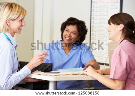 Doctor And Nurses In Discussion At Nurses Station