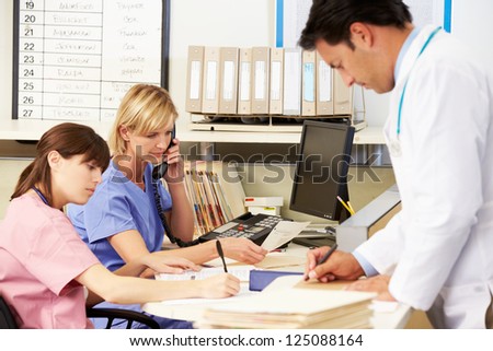Doctor With Two Nurses Working At Nurses Station