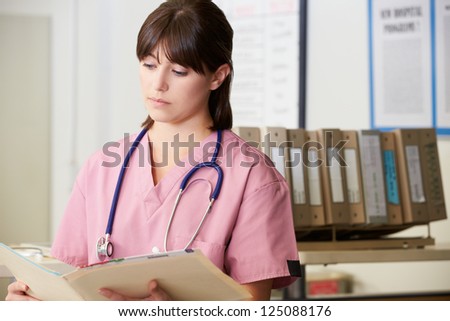 Nurse Reading Patient Notes At Nurses Station